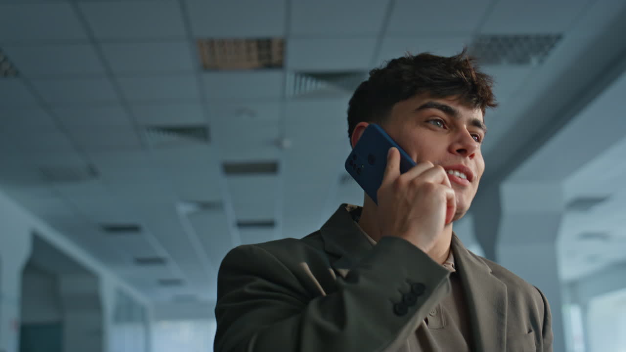 Laughing businessman calling mobile phone at modern business center hall closeup