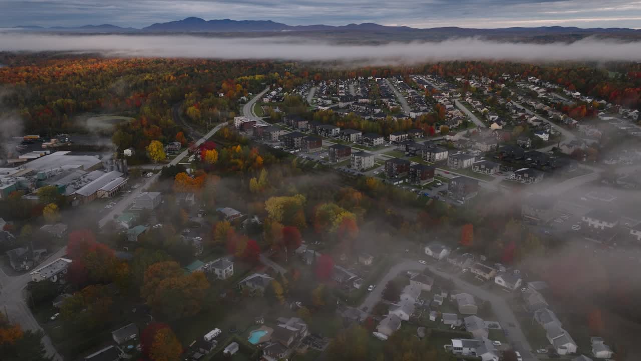 edificios y árboles de otoño a través de franjas de nubes en sherbrooke, quebec, canadá durante la temporada de otoño