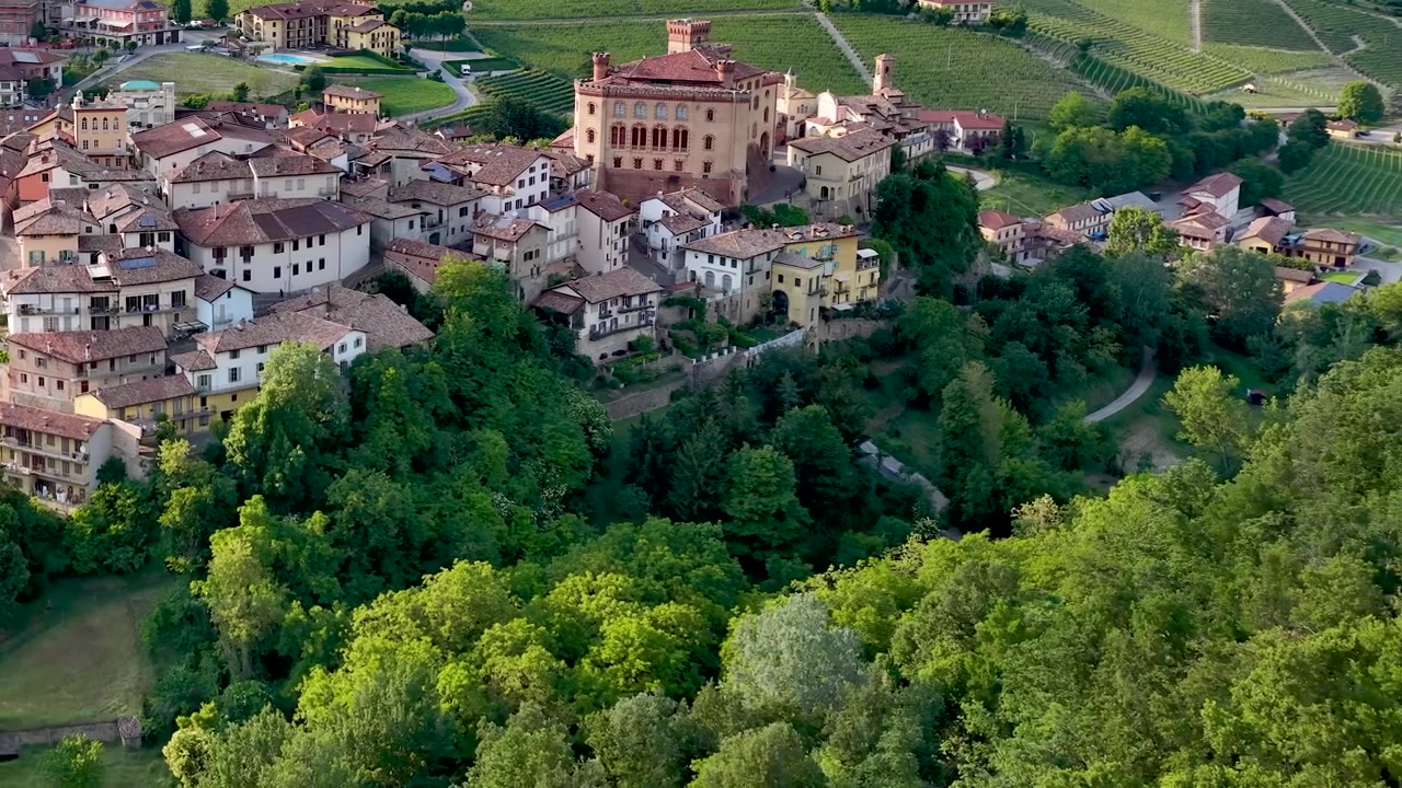 La telecamera del drone si muove sullo storico borgo e castello di Barolo nella rigogliosa campagna piemontese.