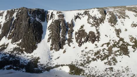 Drohnenaufnahmen-Aus-Der-Luft,-Die-Langsam-über-Einem-Wunderschönen-Zugefrorenen-Loch-Etchachan-Zu-Einer-Dramatischen-Und-Imposanten-Eisbedeckten-Felswand-Und-Klippe-Mit-Steilen,-Schneebedeckten-Schluchten-Fliegen