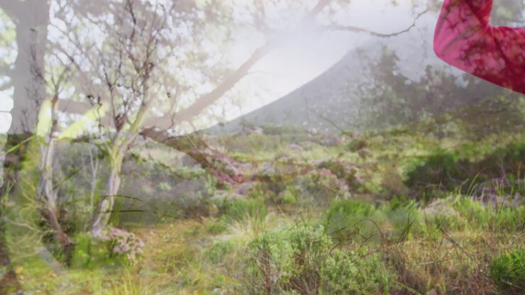 Happy caucasian senior woman hiking in countryside over tree and plants moving in the wind