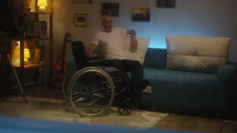 man in wheelchair relaxing on sofa
