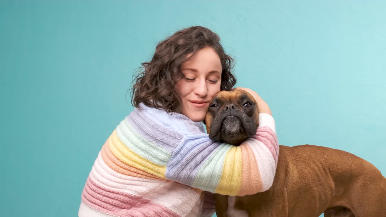 Woman stroking and hugging her boxer dog.