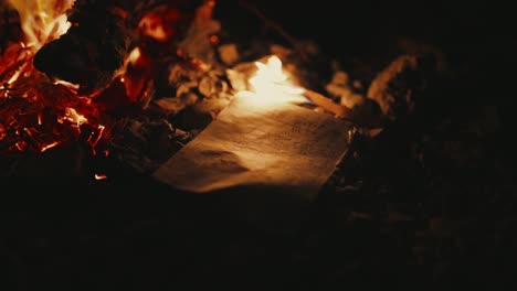 Letter-with-Hebrew-writing-being-lit-by-campfire,-night-shot