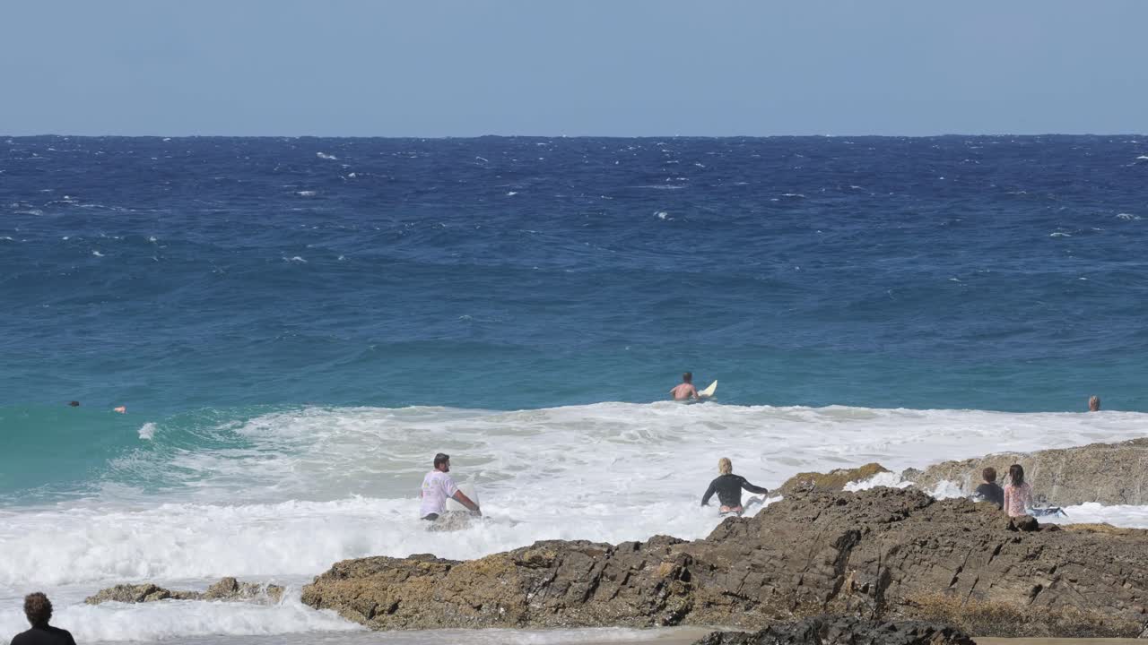 바위 해변 에서 바다 파도 를 즐기는 사람 들