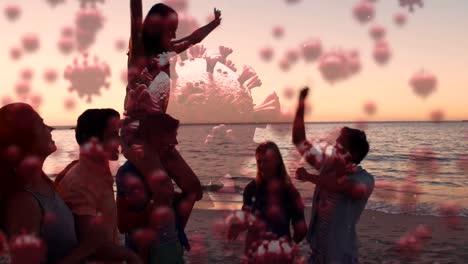 Digital-composite-video-of-covid-19-cells-moving-against-group-of-people-partying-at-the-beach
