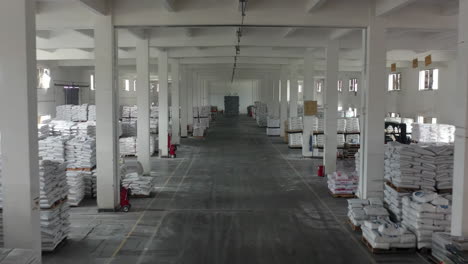 large industrial warehouse filled with stacks of raw materials on wooden pallets and forklifts ready for distribution, processing and forklifts, depicting efficient logistics inventory management
