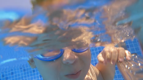 child wearing goggles diving in the pool