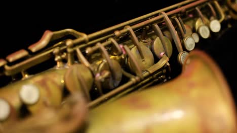 dolly shot of a very old rusty alto saxophone with black background