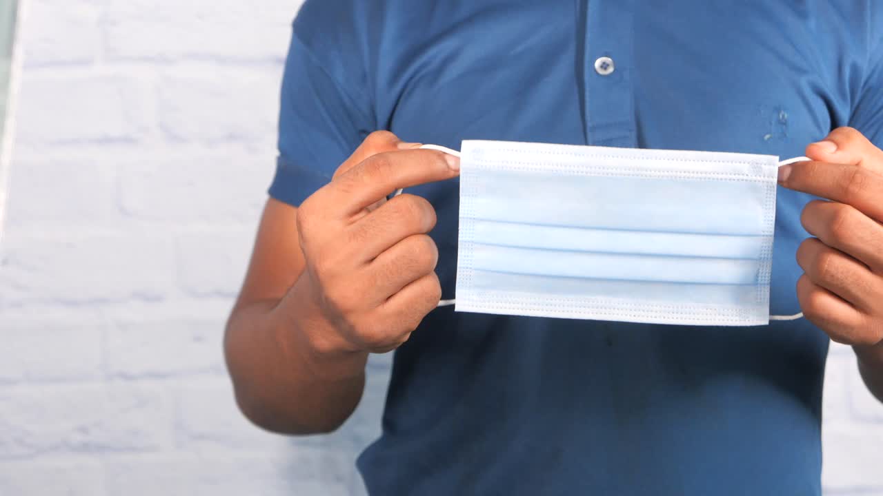 얼굴 마스크를 들고 있는 사람