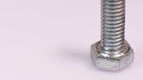 rotating galvanized metallic screw close-up. stainless steel bolt isolated on white background. copy space.