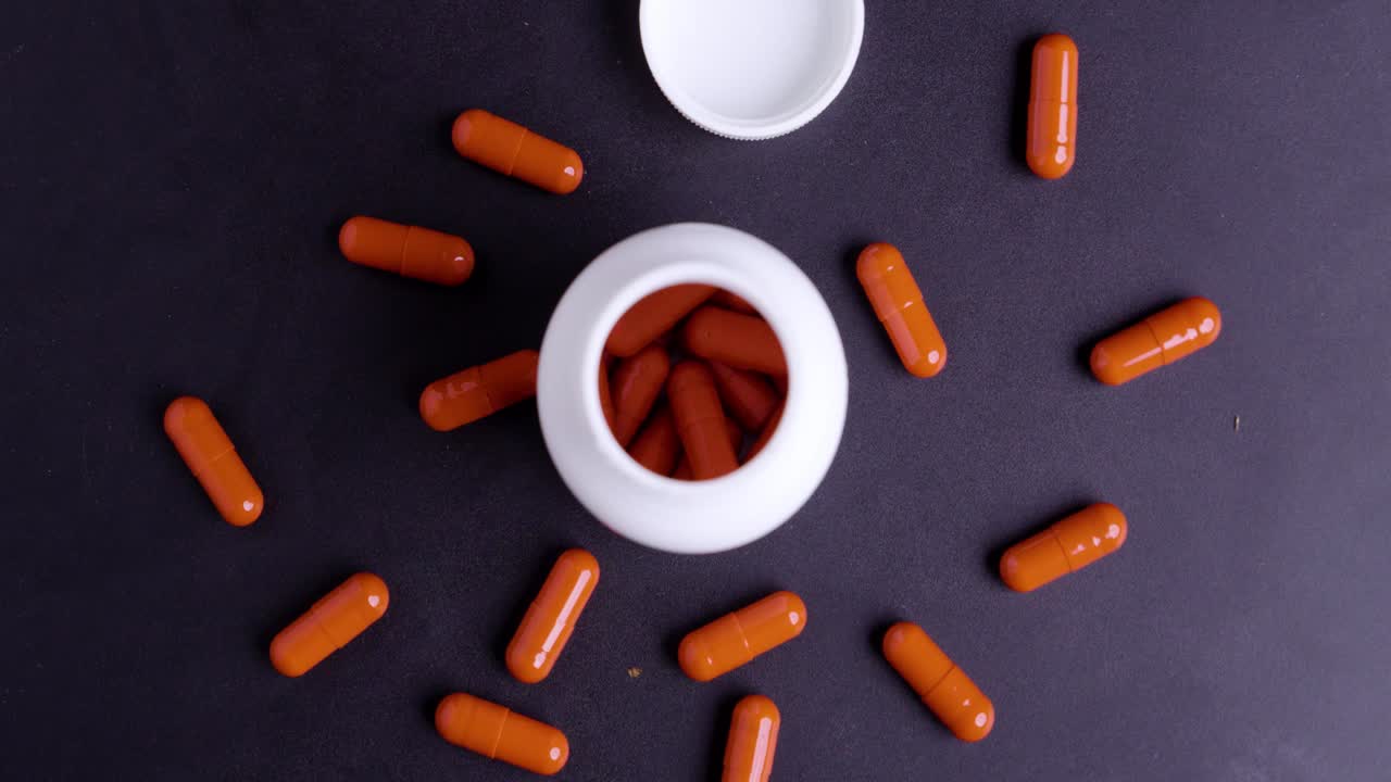 회전하는 빨간 알약과 검정색 배경에 흰색 패키지의 버디아이 샷