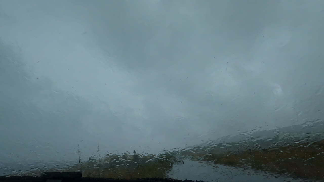 Rain falling on the car window during a downpour, windshield wipers on