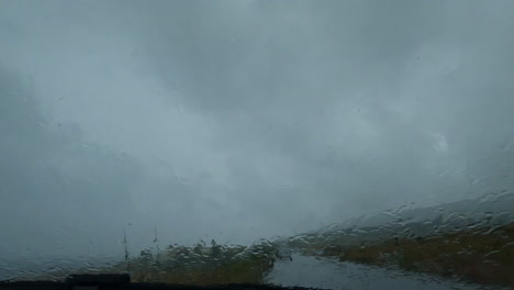 rain falling on the car window during a downpour, windshield wipers on