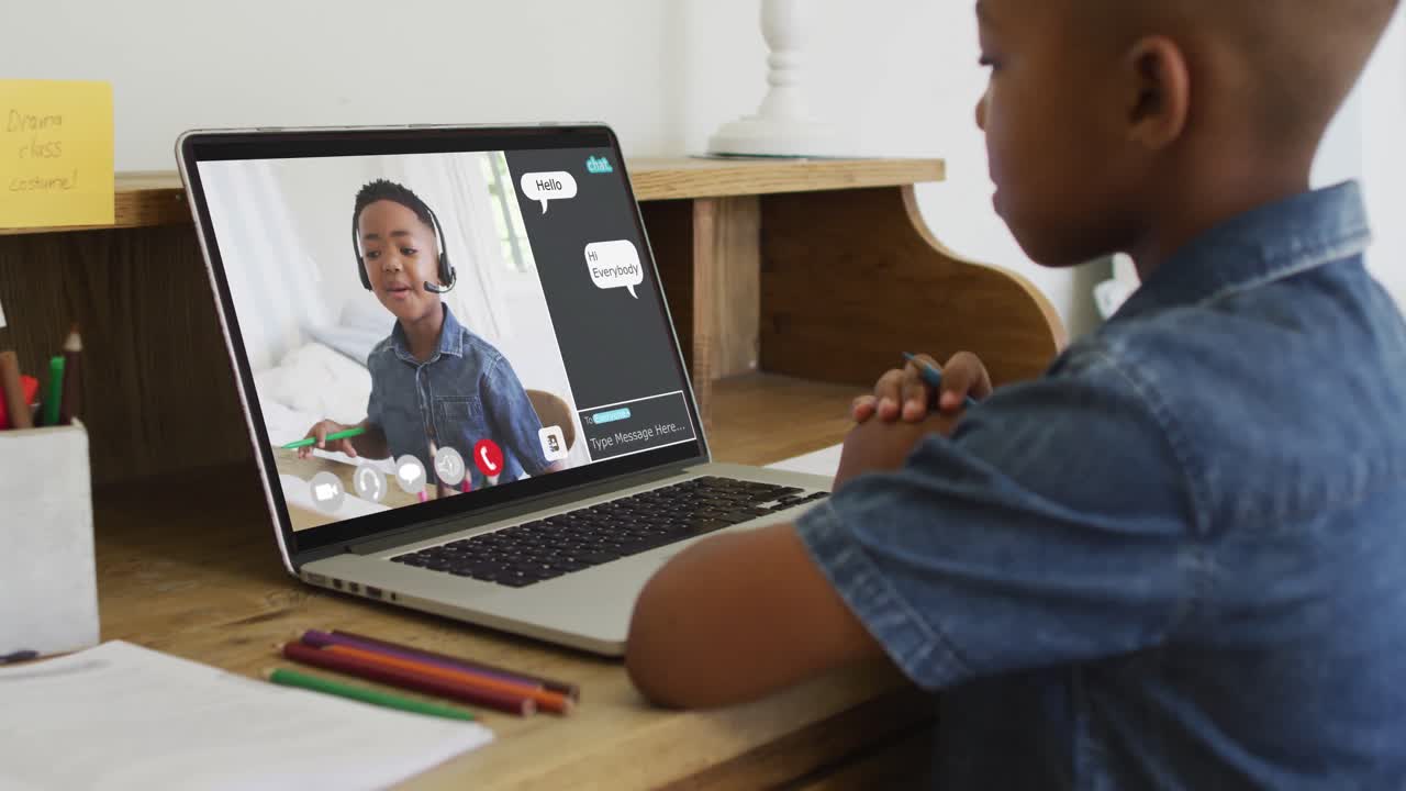 Schoolboy using laptop for online lesson at home, with schoolboy and web chat on screen