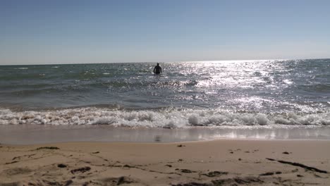 Kaukasischer-Mann-Mittleren-Alters,-Der-Im-Badeanzug-Aus-Dem-Wasser-Des-Michigansees-Am-Strand-Spazieren-Geht