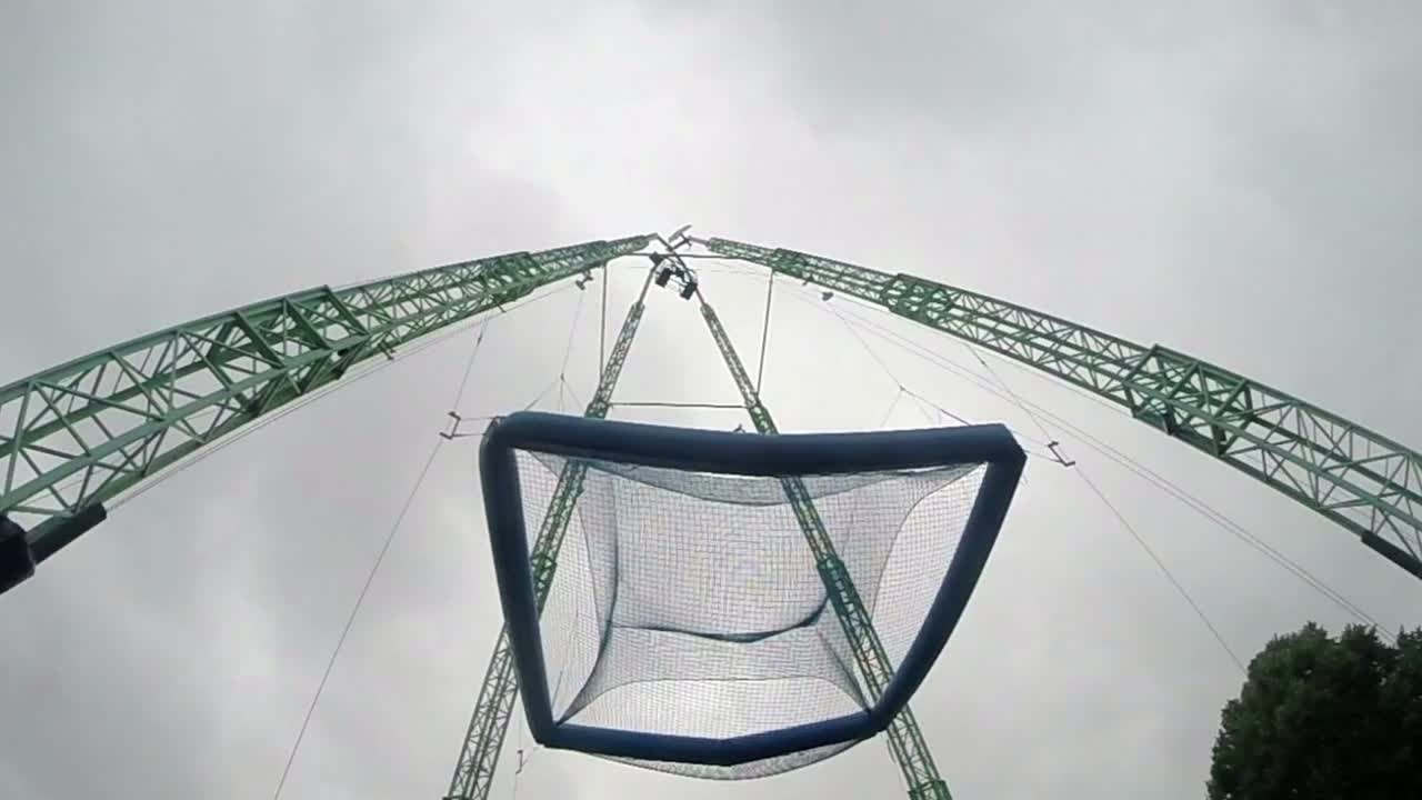 남자는 놀이 공원에서 거대한 매달린 트램폴린에 뛰어든다