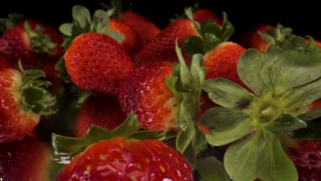 macro view turning strawberries on black glass, 4k shot of healthy fresh fruit, nutritional diet, red strawberry