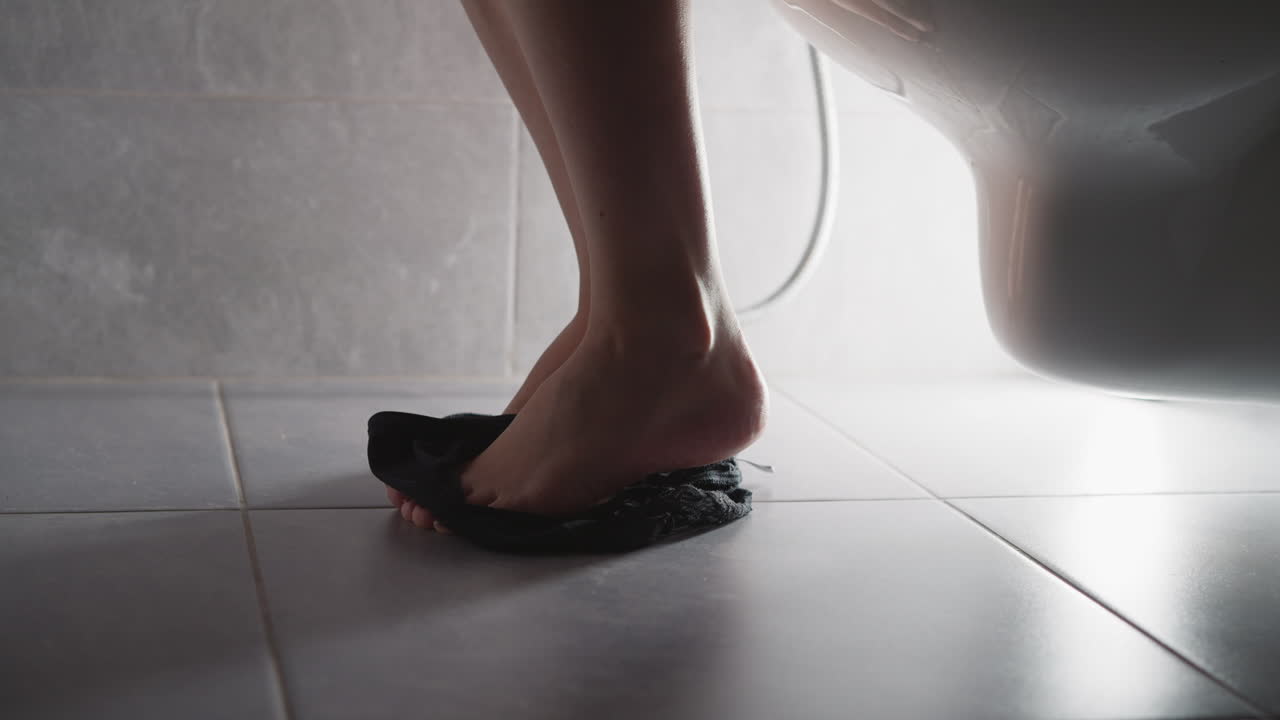 맨발 여자 는 화장실 근처 에 서 있는 속옷 을 벗는다