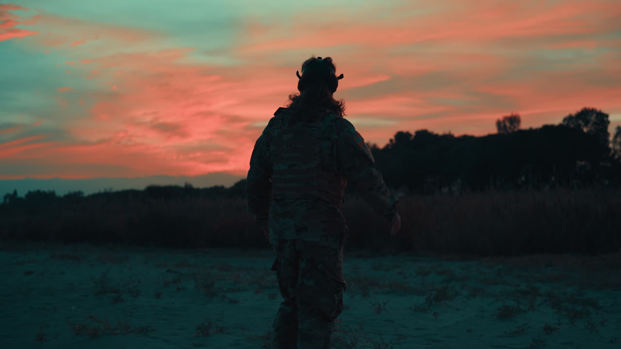Silhuet af en amerikansk soldat med gasmaske, der går på stranden ved solnedgang