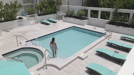 young caucasian woman enters private swimming pool on warm sunny day