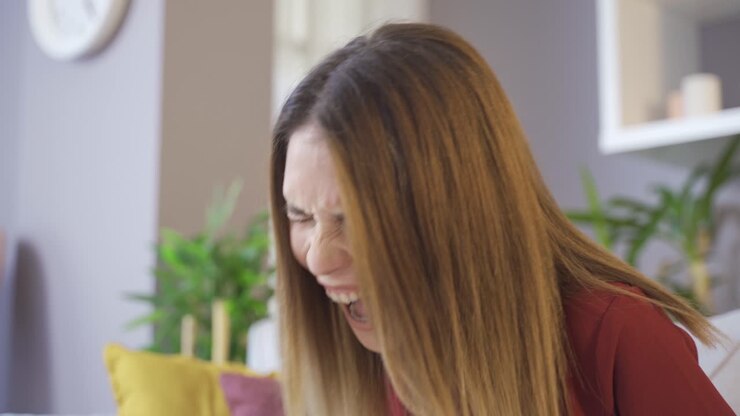 A woman grits her teeth then screams as she strains and pushes.