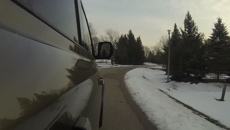 Exterior-view-of-SUV-driving-through-a-snow-covered-neighborhood