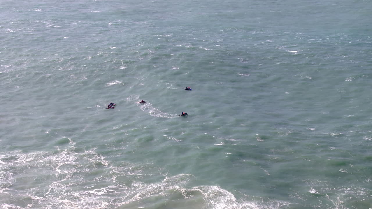 Aerial drone shot of jet ski riders and surfers waiting for waves in the Atlantic Ocean on a day with giant waves in Nazaré, Portugal, Europe. Big wave surfing town