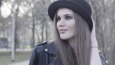 woman in black hat and leather jacket in a park