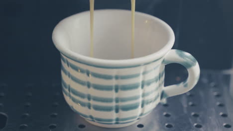 cup getting filled up with fresh brewed coffee close up