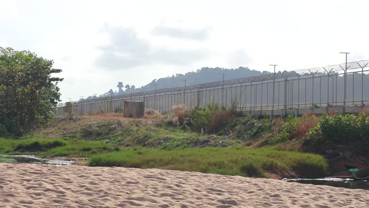 A tranquil beach scene in Phuket, Thailand, with lush greenery, distant hills, and soft natural lighting