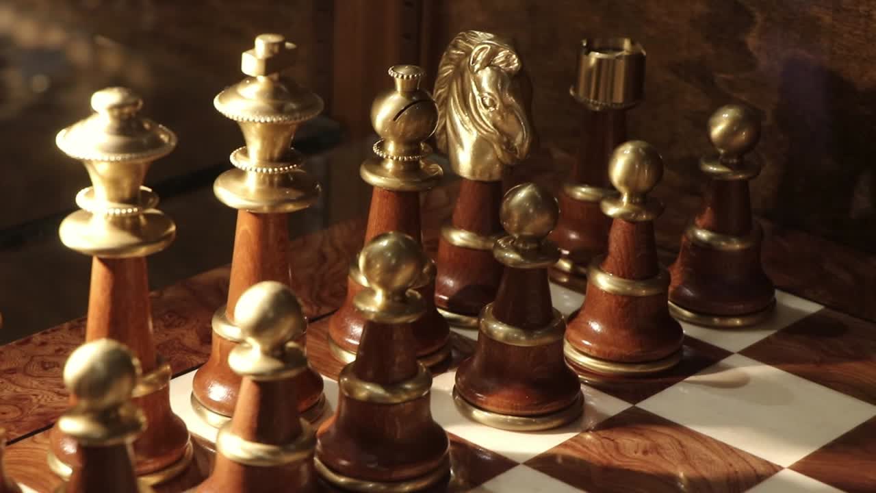 Nærbillede af et luksuriøst skaksæt i træ og guld på et elegant skakbræt.