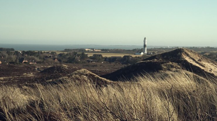 Dune a Sylt in una giornata ventosa con il faro "Langer Christian" e il Mare del Nord sullo sfondo