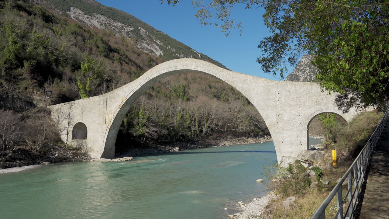 Ampia vista panoramica del Ponte di Plaka, l'iconico ponte ad arco in pietra nell'Epiro, in una giornata limpida e soleggiata. Fiume Arachthos