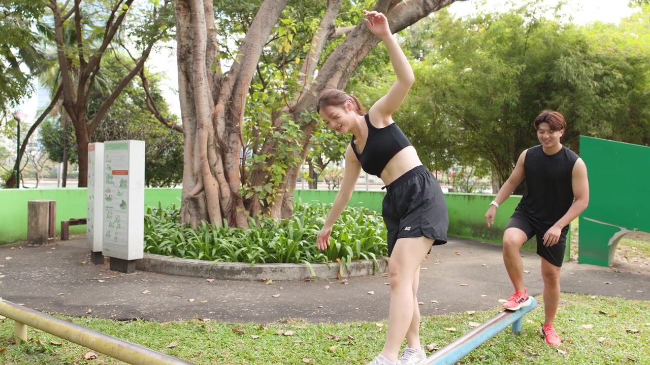 Una pareja tailandesa en forma practica el equilibrio en barras en una zona de fitness al aire libre y soleada en un parque.