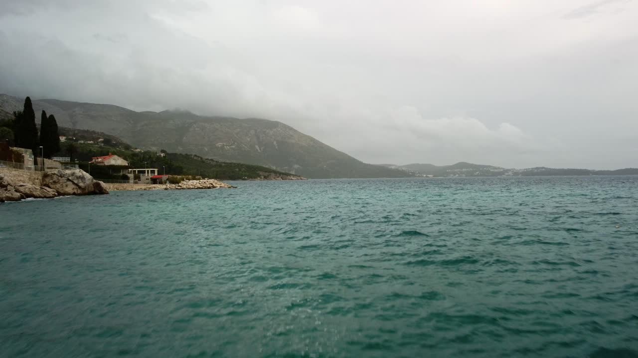 Aerial Drone 4k video from Mlini Plaza Beach down low and then out across the waves to the bay, Mlini, Croatia