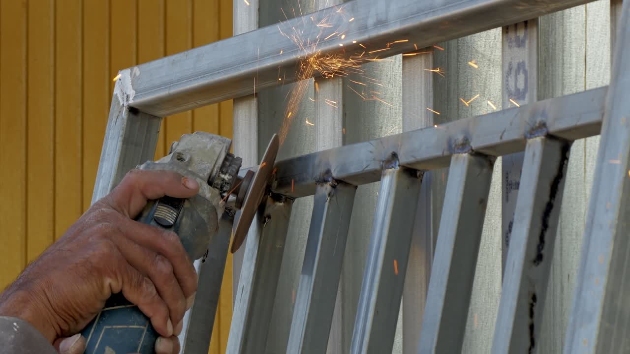 Un trabajador cualificado utiliza una amoladora para generar chispas mientras fabrica metal en un taller