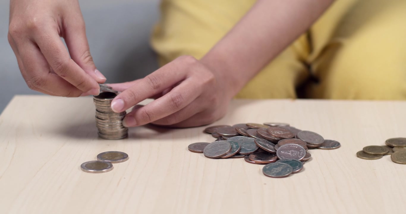 Una persona organizza monete su un tavolo, evidenziando le capacità di gestione del budget e l'alfabetizzazione finanziaria.