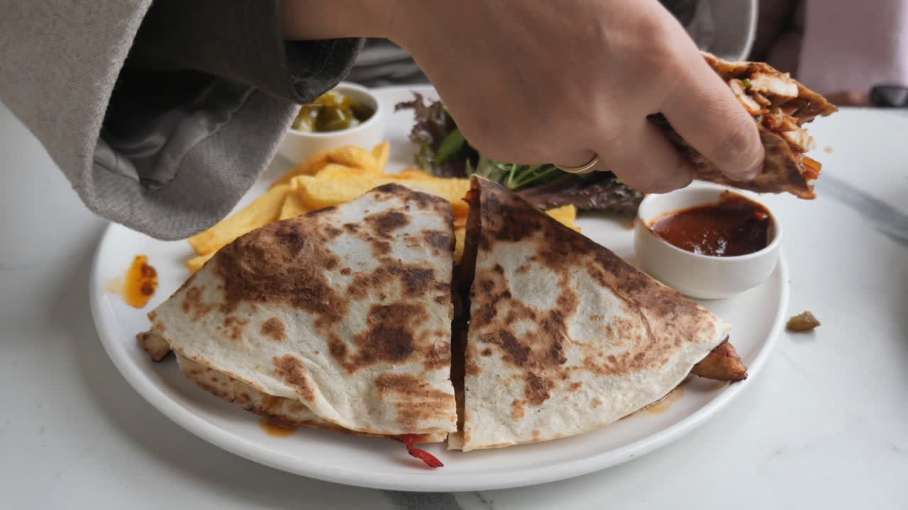 Close-up of Hand Dipping Quesadilla into Sauce