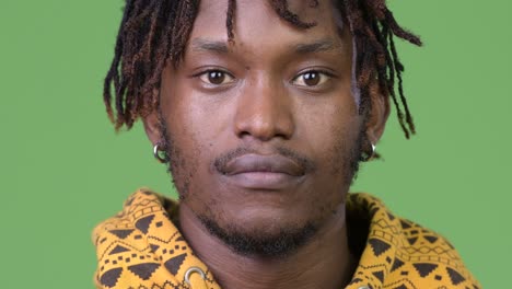 young handsome african man against green background