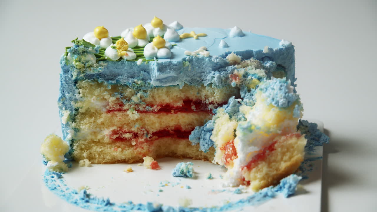 Round cake with blue-colored icing sliced in half showing three layers and a fork picking up the pieces