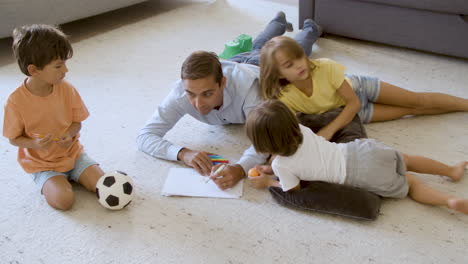 sibling kids and dad lying on warm floor with cushions