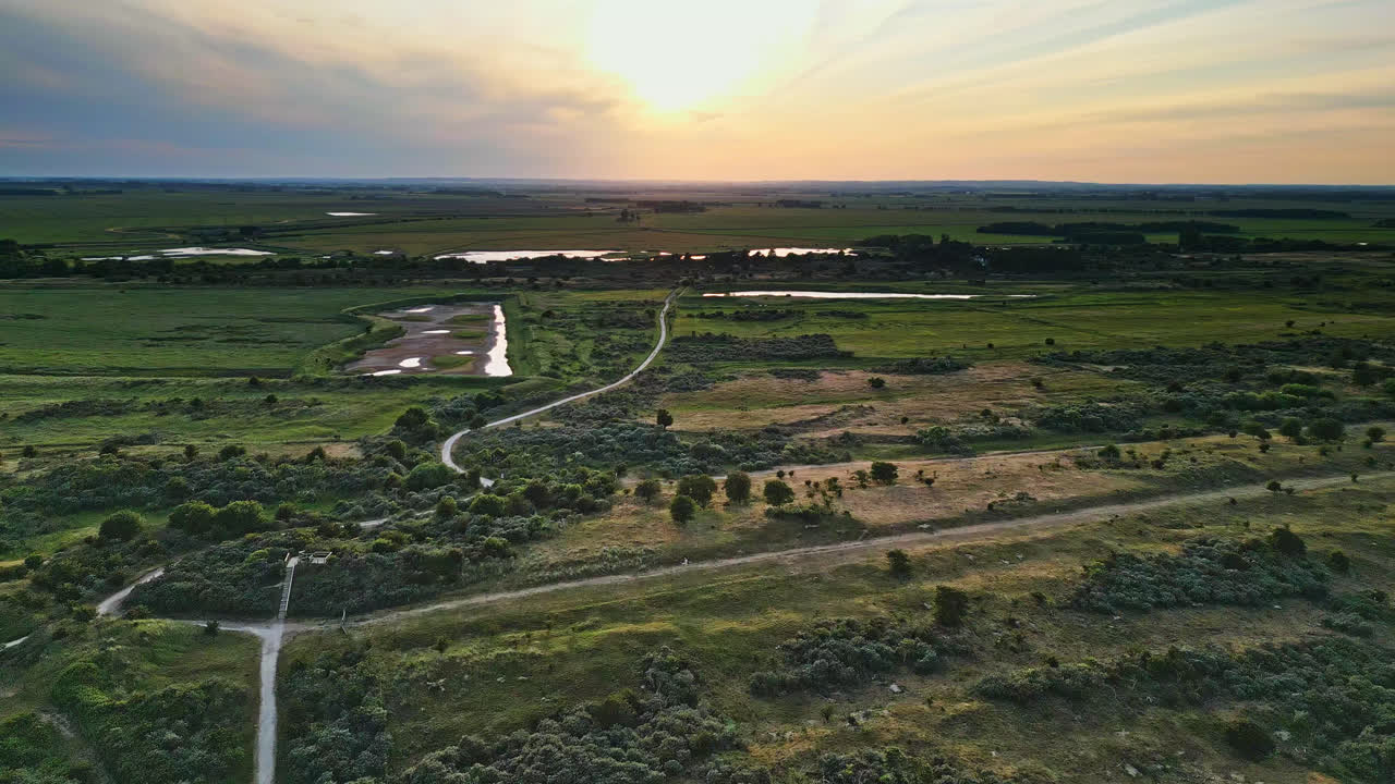 откройте для себя идиллическое очарование прибрежной сцены золотого часа с помощью захватывающих воздушных снимков: устье реки, песчаные берега, океан и болота