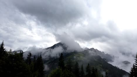 timelapse, pan left to right, showing the mountain alpsitze of german alps with many clouds wrapping around during evening time after a heavy storm