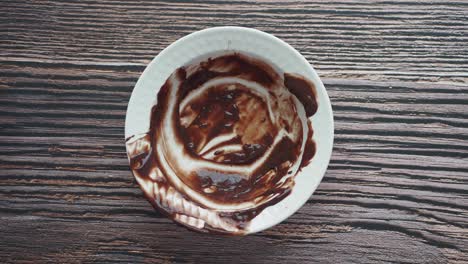 cuenco blanco vacío con residuos de chocolate en una mesa de madera