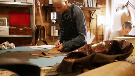 craftswoman cutting leather with scissors