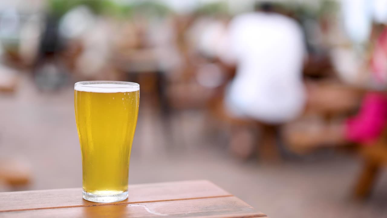 un solo vaso de cerveza en foco en una mesa de madera