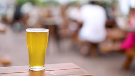 a single beer glass in focus on a wooden table