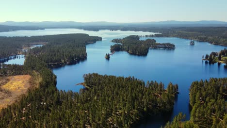 Vista-Aérea-Del-Agua-Tranquila-Del-Lago-Rodeada-De-árboles-Verdes-En-Busjon,-Dalarna,-Suecia---Disparo-De-Drones