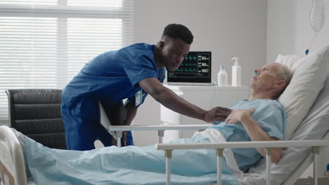 a black doctor of african appearance is talking to an elderly patient lying on the bed of the clinic. the cardiologist advises the patient. the neurologist conducted diagnostics